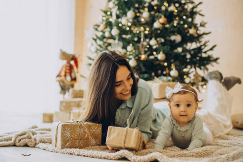 mother-with-her-baby-daughter-with-gift-boxes-by-christmas-tree
