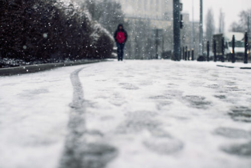 low-angle-shot-person-walking-snow-covered-sidewalk-snow